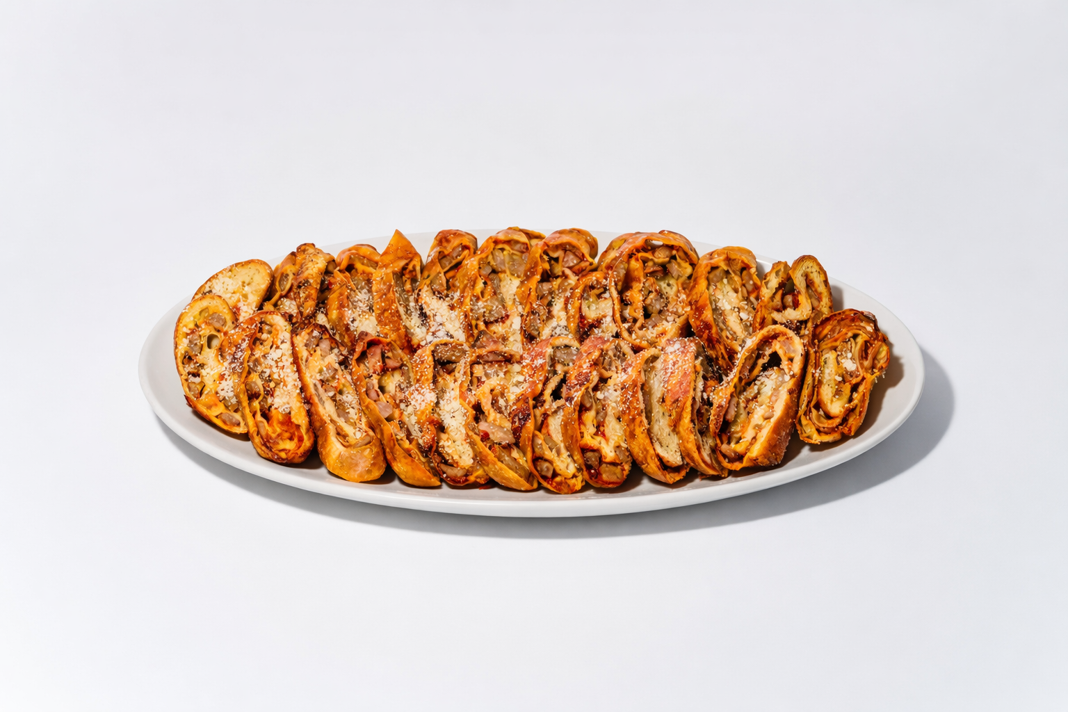 Platter of sliced baked pinwheels topped with grated cheese.