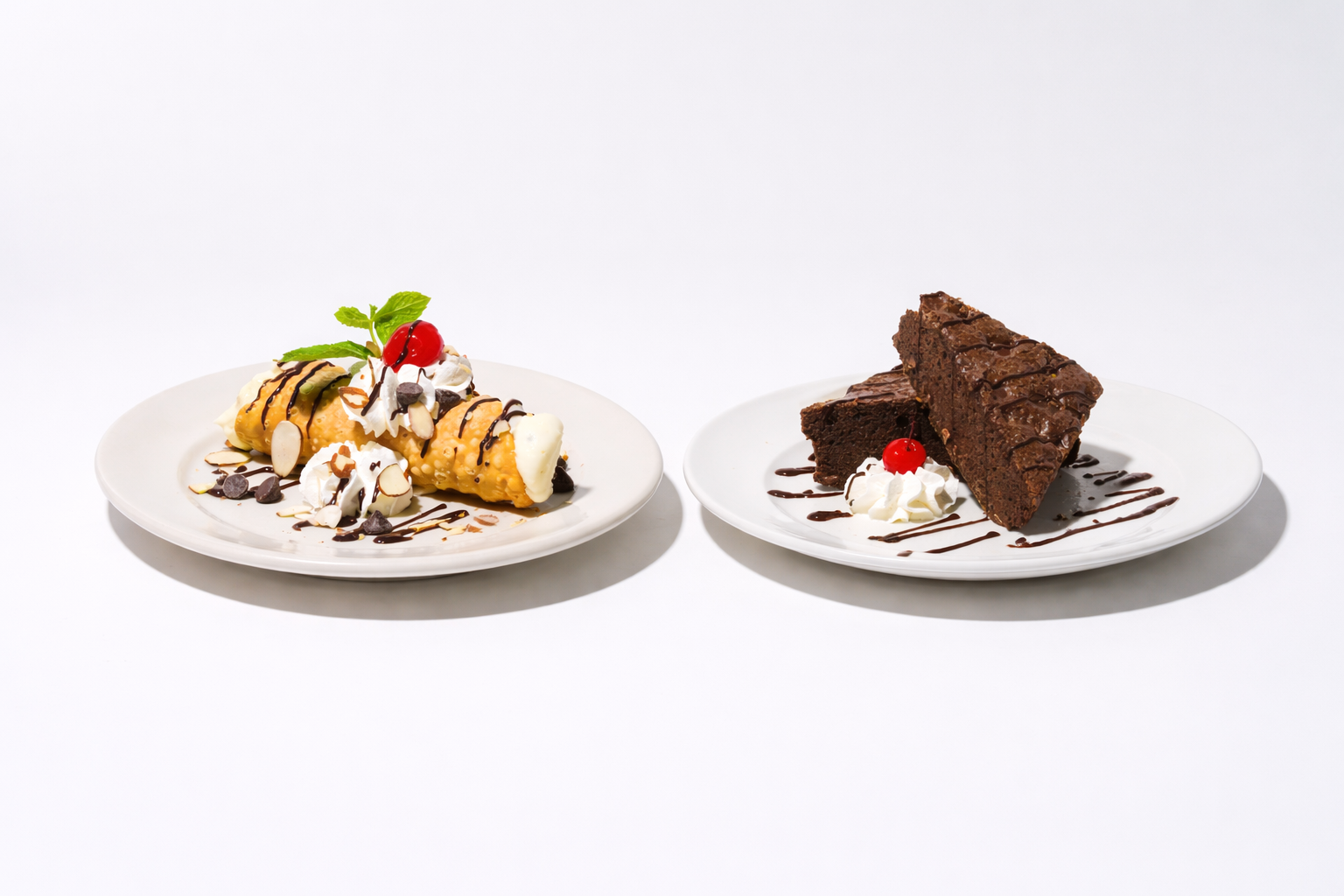 Dessert plates with a cannoli topped with whipped cream and a brownie slice drizzled with chocolate.